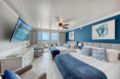 a hotel room with two beds and a flat screen tv at EPIC Gulf & Beach Views with Balcony, Beach Supplies, & Pool in St. Pete Beach