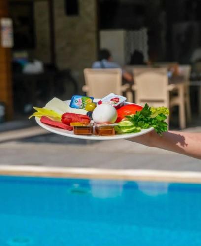 una persona sosteniendo un plato de comida junto a una piscina en Cemal Bey Hotel, en Alanya