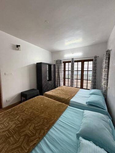 a bedroom with two beds and a window at Sathya Holidays Evermist Stay in Ooty