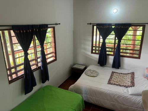 a bedroom with two beds and two windows at XayLa Agro Hostel Curití in Estación El Salto