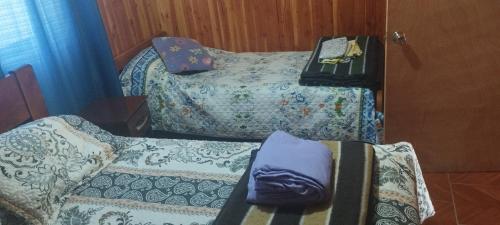 a room with two beds and a table with a bedskirts at Cabaña 1 Dos Laureles in Panguipulli