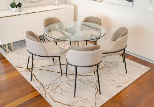 a glass dining table and chairs on a rug at GuestReady - Premium stay in Funchal in Funchal
