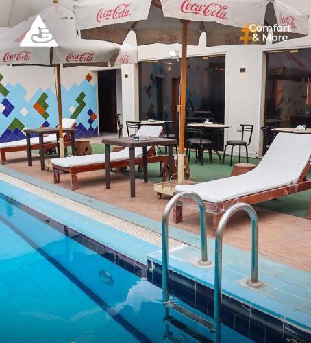 a swimming pool with tables and umbrellas and chairs at Arafa Hotel - فندق عرفه الجديد in Tanta