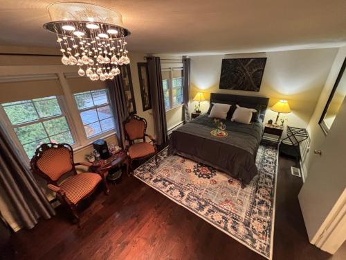 a bedroom with a bed and two chairs and a chandelier at Vintage Pines Guest House in Niagara on the Lake