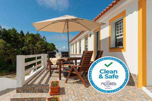 a patio with a table and an umbrella at Casa da Figueirinha in Calheta de Nesquim