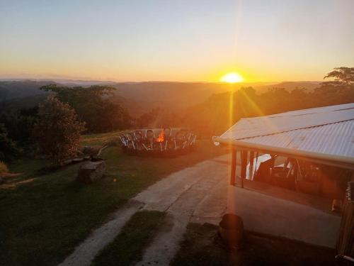 Louis at Magwa Falls في Lusikisiki: غروب الشمس فوق منزل به صف من براميل النبيذ