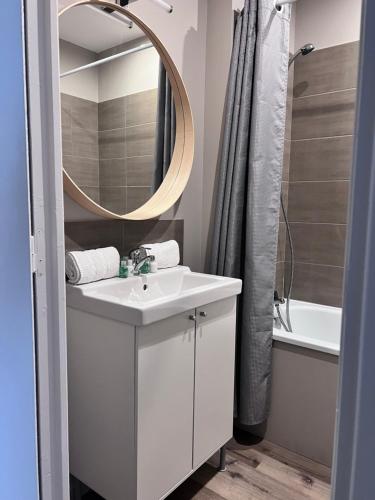 een badkamer met een witte wastafel en een spiegel bij Le Clos de Manon in Carcassonne