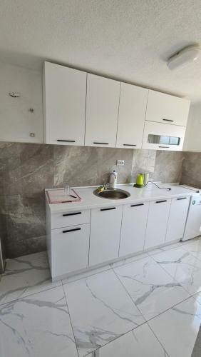 a white kitchen with a sink and white cabinets at Villa Milla near Autopat e 75 in Veles