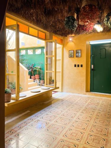 a large room with a green door and some plants at Kuka y Letras in Mérida