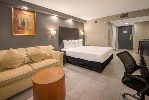 Coast Nisku Inn & Conference Centre في نيسكو: غرفة فندق بها سرير وأريكة