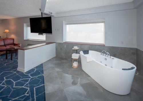 Coast Nisku Inn & Conference Centre في نيسكو: حمام مع حوض استحمام وتلفزيون