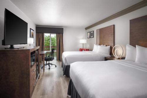 a hotel room with two beds and a flat screen tv at Aiden Austin City Hotel in Austin