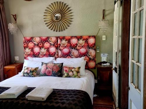 a bedroom with a large bed with a floral headboard at Koekeloer Selfcatering Cottages in Nieu-Bethesda