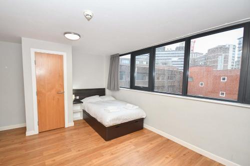 ein Schlafzimmer mit einem Bett und einem großen Fenster in der Unterkunft Convenient Budget Studio in Central Sheffield in Midland