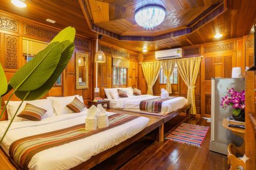 Suchanan Resort Rayong في بان تشانغ: سريرين في غرفة بجدران خشبية وأرضيات خشبية