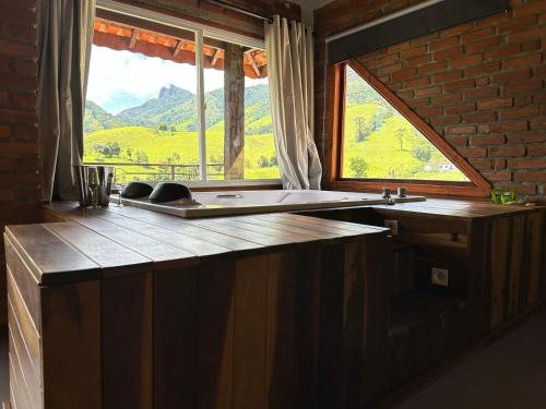 eine Küche mit einem Waschbecken und einem großen Fenster in der Unterkunft Chalés das Cachoeiras - Amor Perfeito in Resende