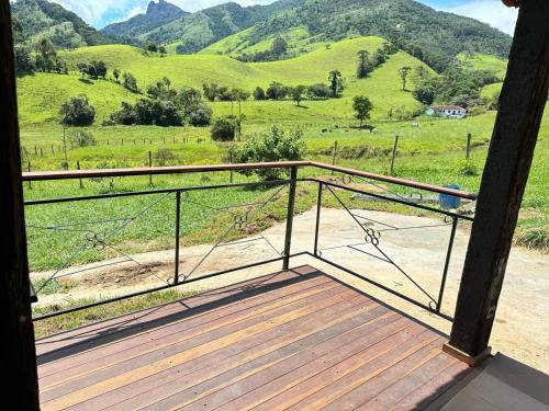 eine Holzveranda mit Bergblick in der Unterkunft Chalés das Cachoeiras - Amor Perfeito in Resende