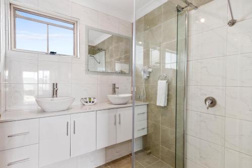 een badkamer met 2 wastafels en een glazen douche bij Swansea Cottages & Lodge Suites in Swansea