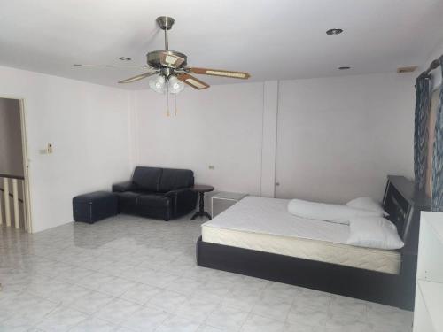 a bedroom with a bed and a couch and a ceiling fan at Doze House Patong Phuket in Patong Beach