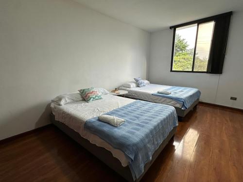 two beds in a small room with a window at Apartamento de lujo en Tequendama, ubicación privilegiada in Cali