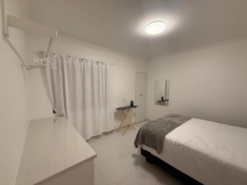 a white bedroom with a bed and a window at 268 Self-catering Apartments in Swakopmund