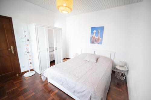 a bedroom with a white bed and a wooden floor at Ferienhaus Treibholz in Funchal