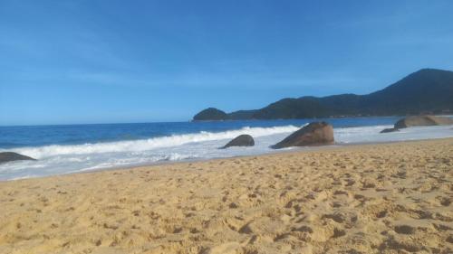 De la rosa y el canto de los pájaros في باراتي: شاطئ رملي مع صخور في الماء