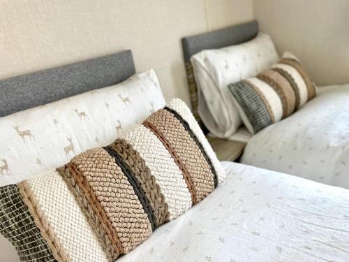 Sea View Chalet Steps from Durdle Door Sleeps 6 في ويست لولوورث: مجموعة من الوسائد فوق السرير