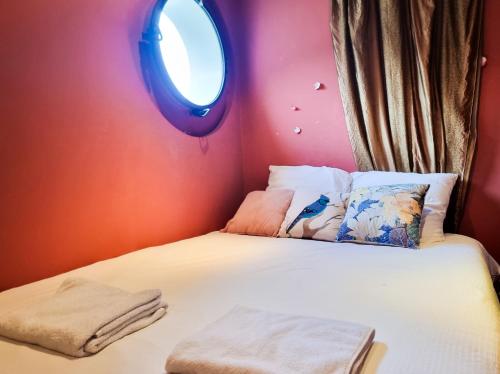 a small bedroom with a bed with a round window at EXIGEHOME-Large houseboat with spa near Paris in Saint-Cloud