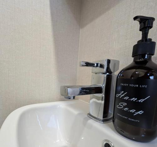 Sea View Chalet Steps from Durdle Door Sleeps 6 في ويست لولوورث: زجاجة من صابون الشعر موضوعة على حوض الحمام