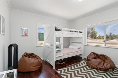 a bedroom with white bunk beds and a window at Playgrounds in Lancelin