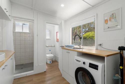 a white bathroom with a washing machine in it at Playgrounds in Lancelin