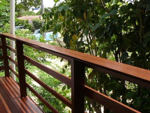 una ringhiera in legno su un portico con un albero di Chalé Borboletas Centro Pipa RN a Pipa