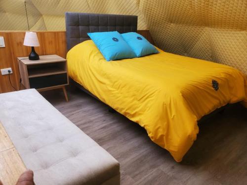Permasalud Glamping : سرير أصفر مع وسائد زرقاء في الغرفة