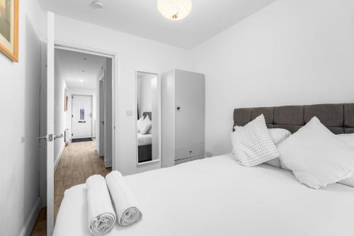 a white bedroom with a large bed with white pillows at 2 Bedroom house,BrownhillRd SE6 in London