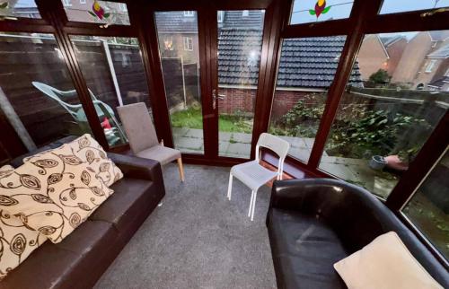 a living room with a couch and chairs and windows at Sorrell Gardens Guest House in Newcastle under Lyme