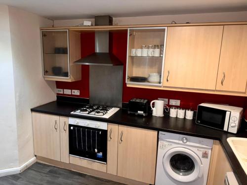 a kitchen with a stove and a washing machine at Sorrell Gardens Guest House in Newcastle under Lyme