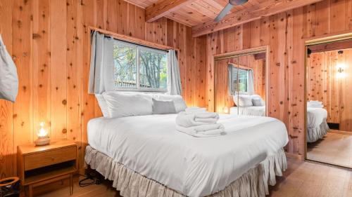 a bedroom with a bed with white sheets and a window at 5BDR Hot Tub Deck Firepit Mins to Village Lake The Hilltop by AvantStay in North Shore