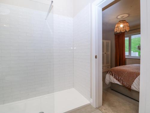 een badkamer met een douche en een bed bij The Willows in Trearddur