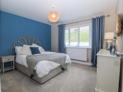 een blauwe slaapkamer met een bed en een raam bij The Willows in Trearddur