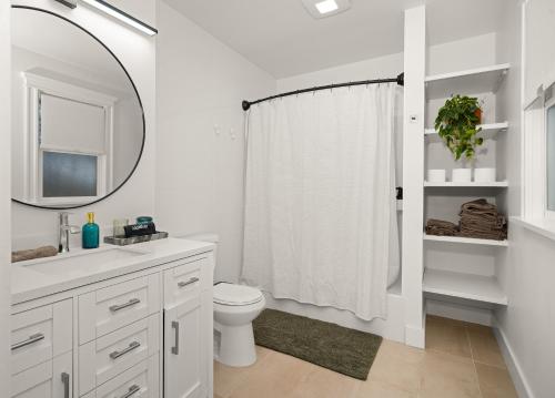 a white bathroom with a toilet and a mirror at New! The South Hill Sanctuary-4 min to Manito Park in Spokane