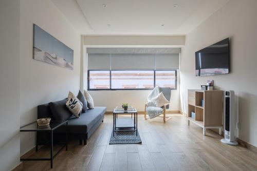 Una sala de estar con un sofá azul y un televisor en ZIELO BRASIL Historic Center, en Ciudad de México