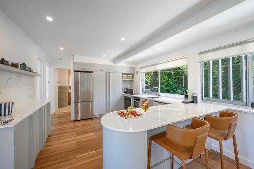 a kitchen with a large white island with chairs at Noosa Escape 2BR Ocean Views, Walk to Beach in Noosa Heads