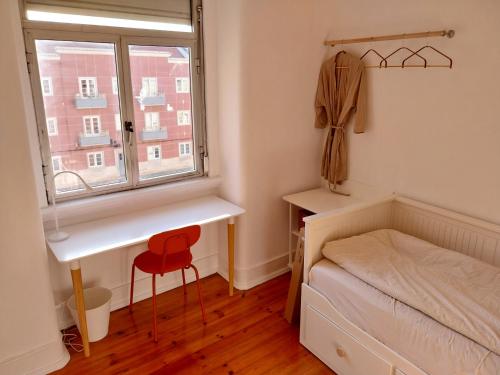 a bedroom with a desk and a bed and a window at Stylish Cacilhas rooms near the ferry to central Lisbon in Almada