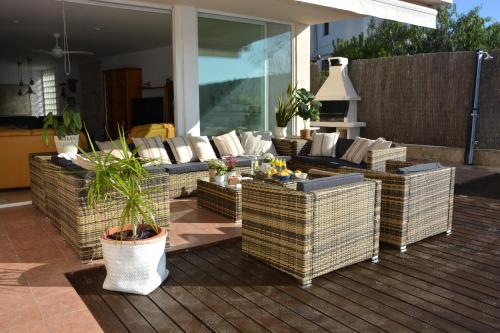 patio con sedie in vimini e divani su una terrazza di Villa Med A 2 kilometros andando de la playa, del puerto de Aguadoç y a 4 del centro de Sitges Muy Soleada todo el dia Capacidad superior a 16 personas NO REQUIERE COCHE a Sitges