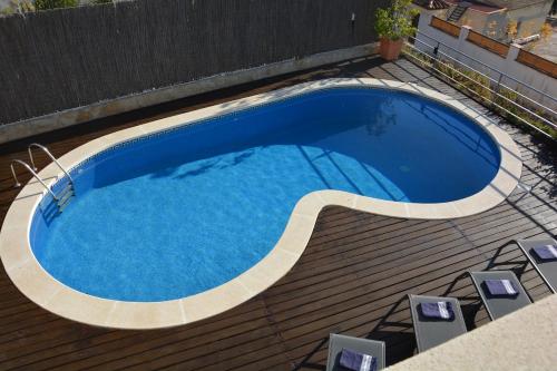 una piscina su un ponte di legno con sedie intorno di Villa Med A 2 kilometros andando de la playa, del puerto de Aguadoç y a 4 del centro de Sitges Muy Soleada todo el dia Capacidad superior a 16 personas NO REQUIERE COCHE a Sitges
