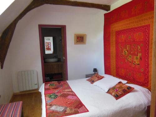 een slaapkamer met een bed met een rood hoofdeinde bij Chambres d'Hôtes des Grands Prés in Argentan