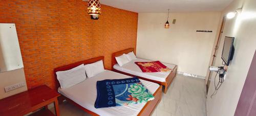 two beds in a room with a brick wall at KSR Aura Homestay in Kodaikānāl