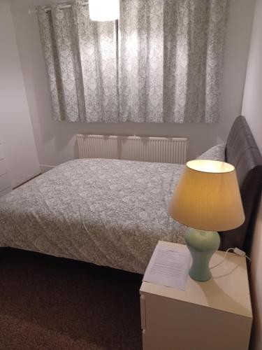 a bedroom with a bed and a lamp on a nightstand at Christian Guest House 1 in Luton