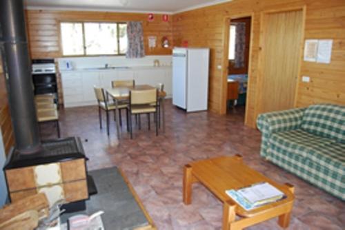 a living room with a couch and a stove at Gumleaves Bush Holidays in Little Swanport
